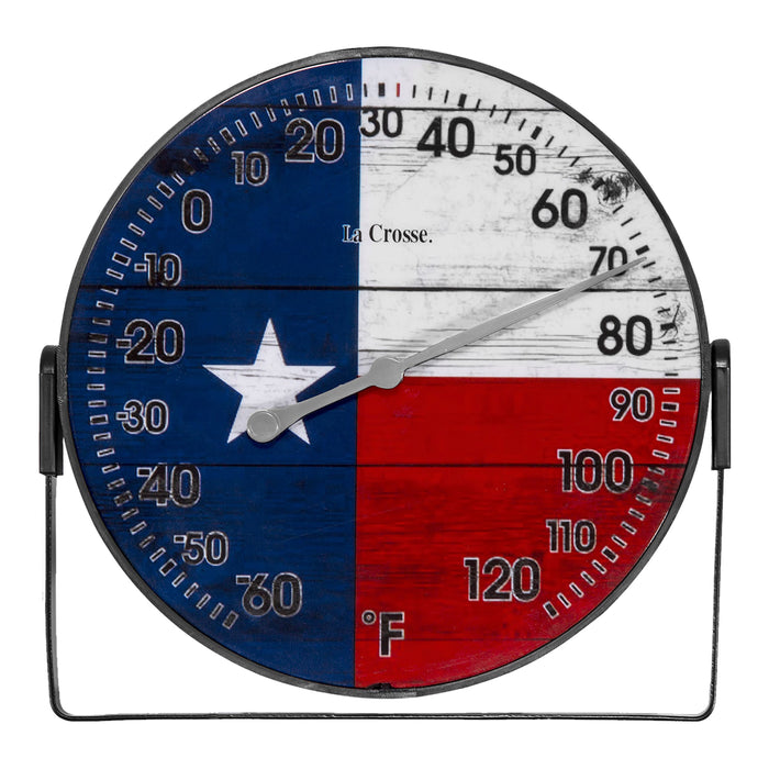 Head-on image of the 104-105TX 5-inch Dial Thermometer with Bracket that is positioned on the bottom. The dial features black numbers on a rustic Americana flag in red, white, and blue with a white star, over rustic weathered boards, surrounded by a black frame with an adjustable bracket for mounting. Featuring a silver pointer that provides the temperature reading in Fahrenheit from -60-120 degrees.