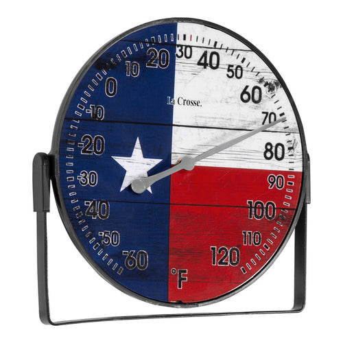 Right-facing image of the 104-105TX 5-inch Dial Thermometer with Bracket that is positioned on the bottom. The dial features black numbers on a rustic Americana flag in red, white, and blue with a white star, over rustic weathered boards, surrounded by a black frame with an adjustable bracket for mounting. Featuring a silver pointer that provides the temperature reading in Fahrenheit from -60-120 degrees.