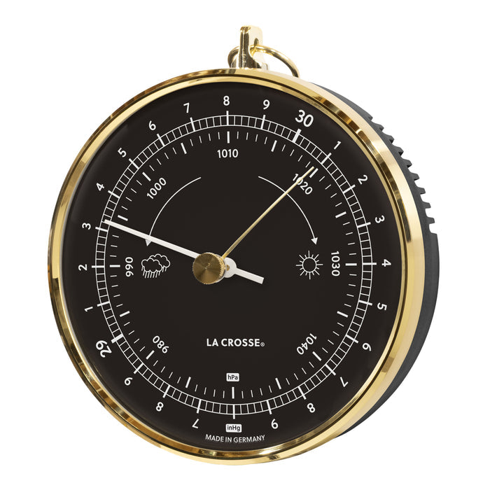 Left-facing image of the 138-1611B Analog Barometer - Black featuring a brass case with a dome lens covering a black dial, brass reference marker, a white pressure indicator, white numbers, icons, and text. The barometer measures the atmospheric pressure in Hectopascals (hPa) and in Inches of Mercury (inHg) Made in Germany.