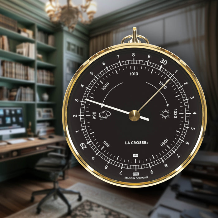 Lifestyle image of the 138-611B Analog barometer with a black dial, white pointer, brass indicator, and brass bezel case displayed in a home office setting, blending classic weather instrumentation with traditional décor.