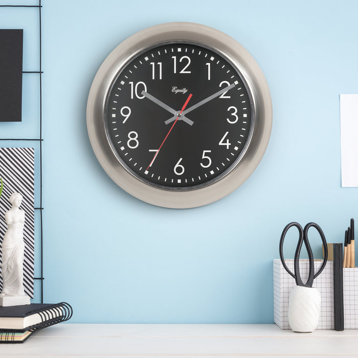 Wall clock with black face and silver frame on a light blue wall.