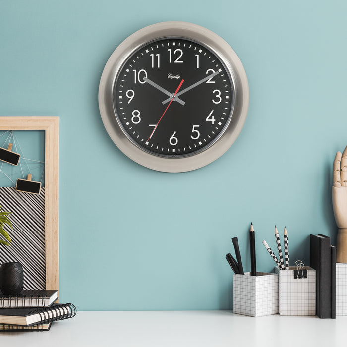 Wall clock on a light blue wall with office supplies below