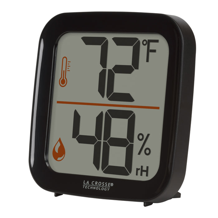 Left-facing image of the 302-1407B Thermometer with Temperature and Humidity - Black. The thermometer features a black square case and a digital screen with large temperature and humidity readings. Next to the digits are corresponding temperature and humidity icons in orange.