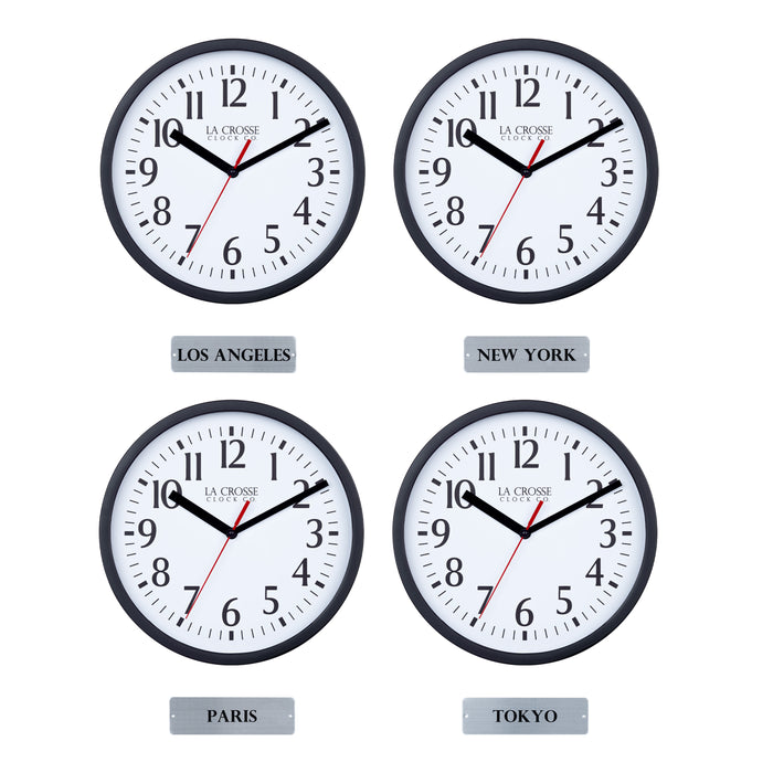 Head-on image of the 404-3020B-4TZ Four Pack 8-inch Basic Wall Clock with City Plaques showing all four clocks. The clocks feature black frames with white dials, black numbers, black hour and minute hands, and a red second hand. Beneath each clock is a small rectangular plaque labeling a city: “Los Angeles,” “New York,” “Paris,” and “Tokyo,” indicating different time zones.