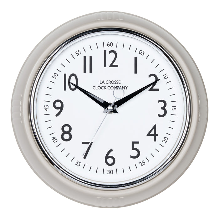 Head-on image of the 404-3024TP 9.5-inch Diner Clock – Taupe. The clock features a retro-style taupe frame with a white dial, chrome bezel, black numbers and minute markings, black metal hands, and a silver second hand.