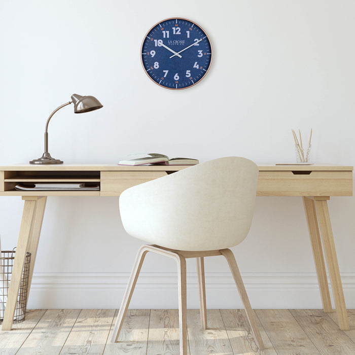 404-3027C Portside Navy blue eleven inch wall clock with white numbers copper time markings and a copper case and white hour and minute hands hanging on a wall over a Scandinavian style desk and chair with light wood flooring
