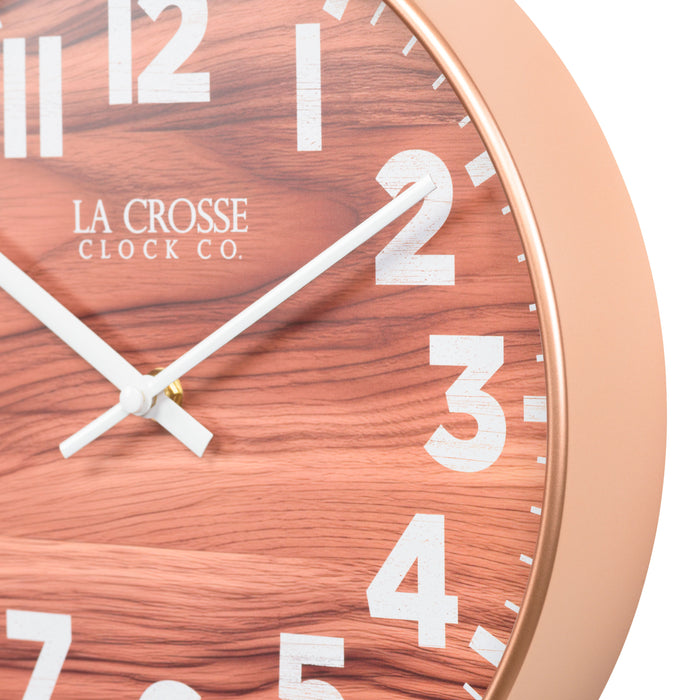 Frame detail of the 10.8-inch Atwood Wall Clock featuring a copper finish frame, a wood design dial, white numbers, and white metal hour and minute hands.