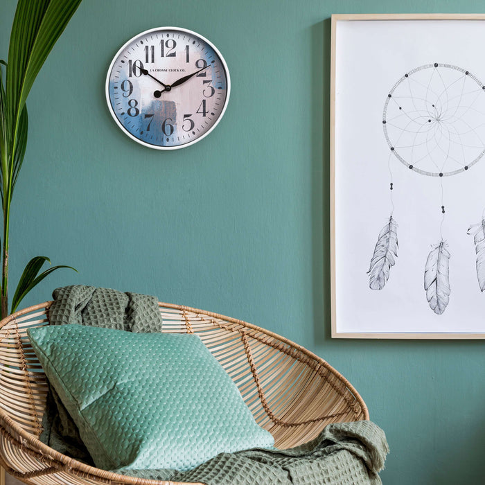 404-3028A 10.8-inch Brushstroke Wall Clock hanging on a green wall with a rattan papasan chair, dream catcher wall art print and a plant