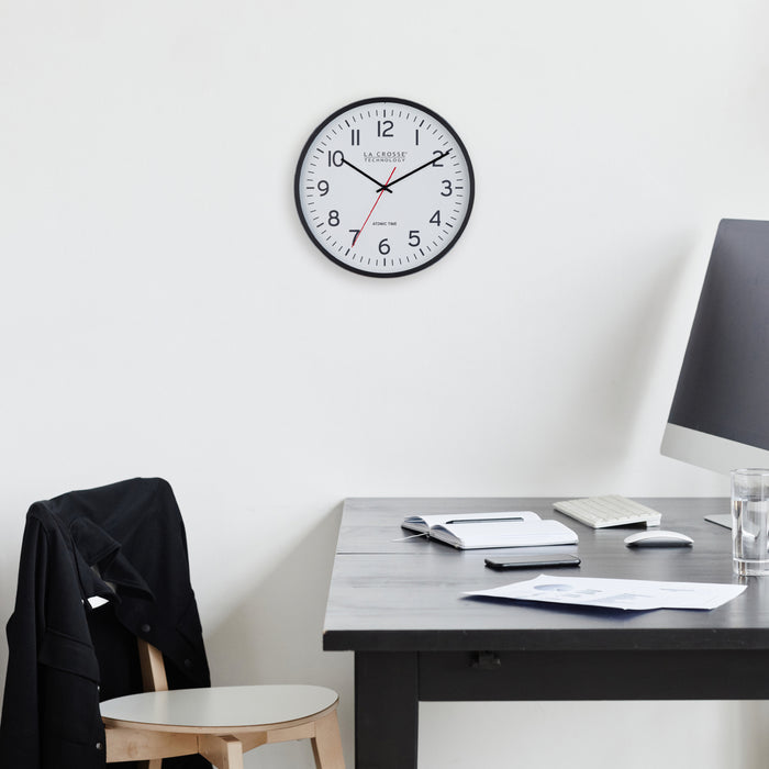404-3730 Wall clock on a white wall above a desk with office items.