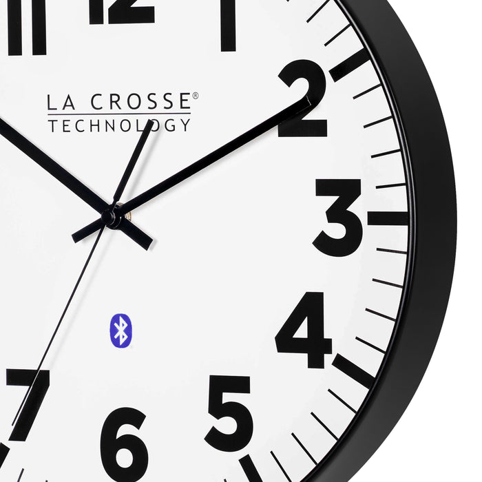 Close-up image of the frame of the 404-4536 14.2-inch Insta-Set Wall Clock with Bluetooth® Technology the clock features a white dial with bold black numbers and markings, a black flush-mount frame, and black hands
