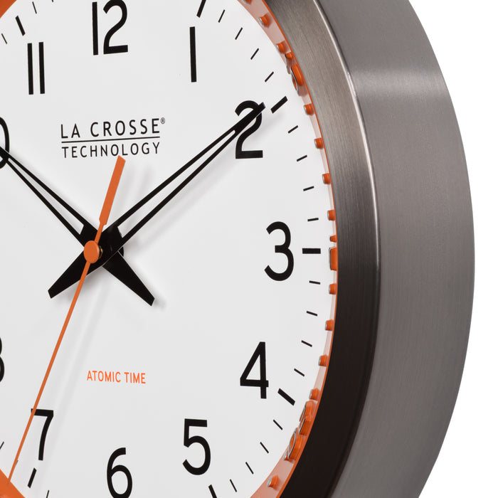 Frame close-up of the 404-87696 10-inch Atomic Metal Wall Clock - Chapter Ring: Orange. The clock features a white dial, an orange chapter ring with seconds indicator, black hands, an orange second hand, and a stainless steel flush-mount frame.