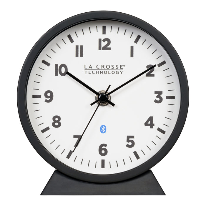 Head-on image of the 437-3816 Insta-Set Table/Wall Clock with Bluetooth® Technology featuring a white dial with bold black numerals, black metal hands, and a black frame with removable base for tabletop or wall hanging placement.