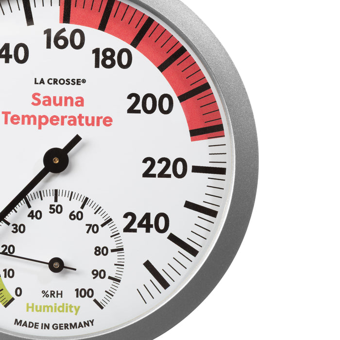 Close-up image of the dial of the 914-612 Sauna Thermometer with Hygrometer. The thermometer features a slimline silver frame, black temperature readings from 65 degrees Fahrenheit to 255 degrees Fahrenheit, with optimal temperature highlighted in red from 158 to 212 degrees Fahrenheit, with a black pointer. The hygrometer displays the humidity readings in relative humidity %RH in black digits from 0 to 100 percent showing the optimal range in green 0 to 20 percent relative humidity with a black pointer.