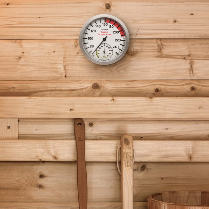Lifestyle image inside a wood sauna with the 914-612 Sauna Thermometer with Hygrometer hanging on the wall. Featuring a slimline silver frame, black temperature readings (65 to 255 degrees Fahrenheit and a hygrometer displays the humidity readings in relative humidity %RH from 0 to 100 percent (optimal range in green 0 to 20 percent) relative humidity with a black pointer.