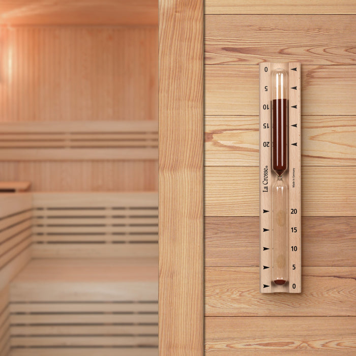 Lifestyle image inside a sauna displaying the  918-631 Sauna Hourglass Timer with wood casing, glass tube, and red sand with markings 0 to 20 minutes and the La Crosse logo with 19 minutes left on the timer