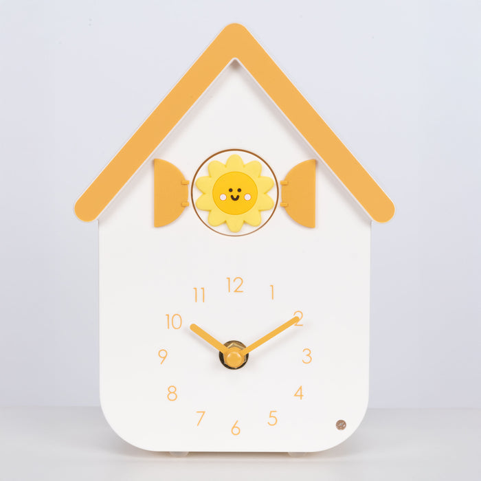 Head on image of W70063, a white house shaped clock with a smiley sun cuckoo with yellow numbers, shutters, roof, and hands