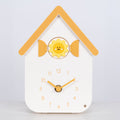 Head on image of W70063, a white house shaped clock with a smiley sun cuckoo with yellow numbers, shutters, roof, and hands