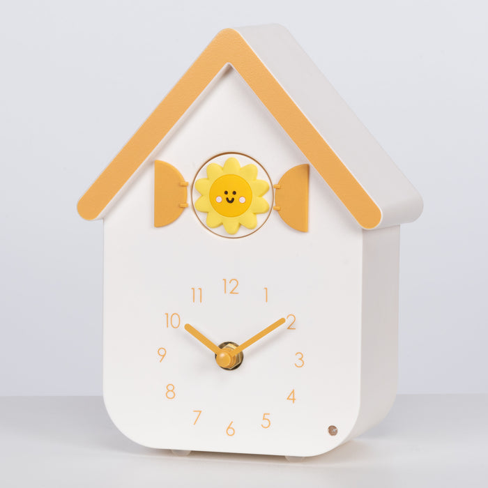 Left facing image of W70063 House shaped clock with a smiley sun cuckoo on a white background with yellow numbers, shutters, roof, and hands